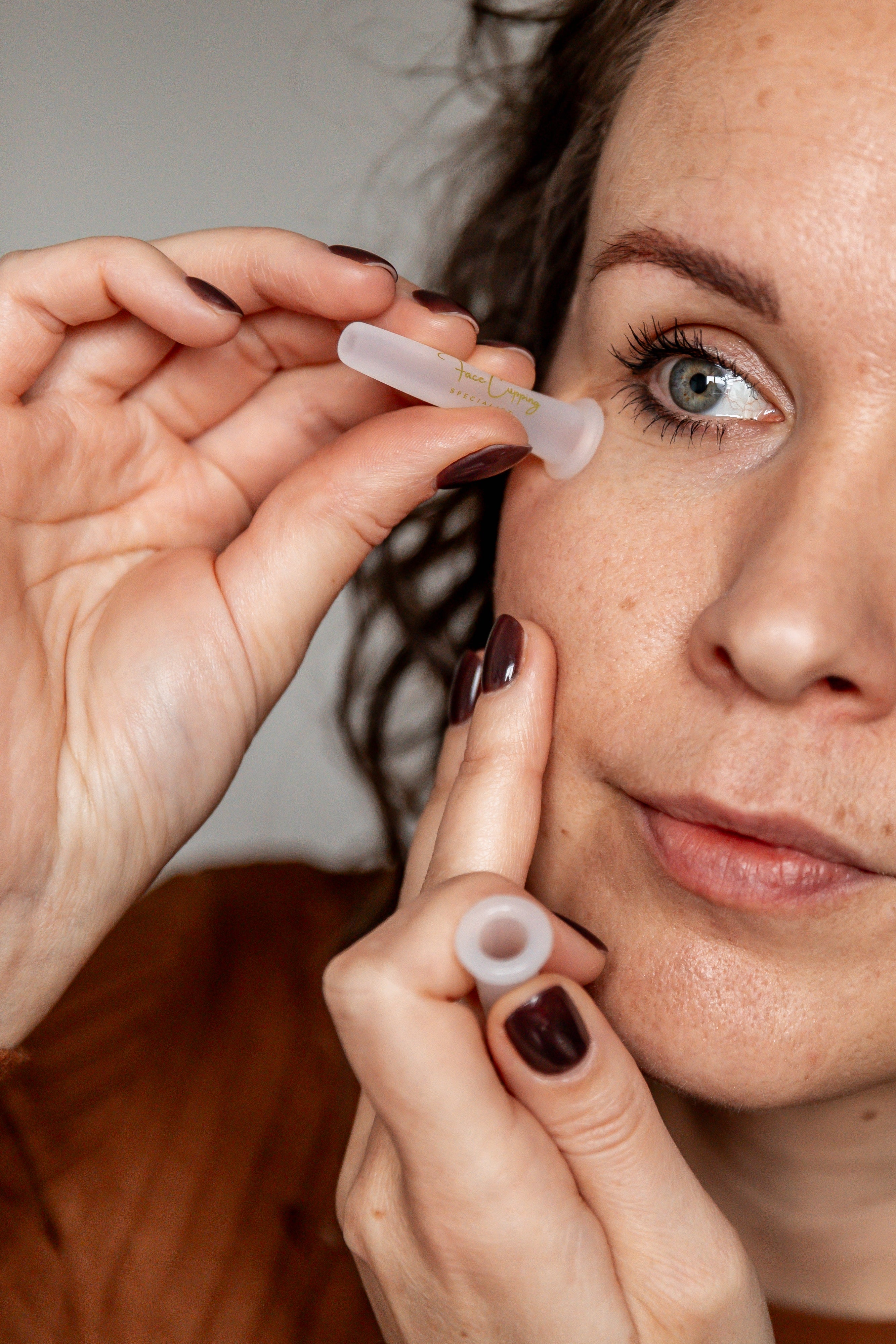 Foto van de Face Cupping Specialist met mini cups onder haar oog.