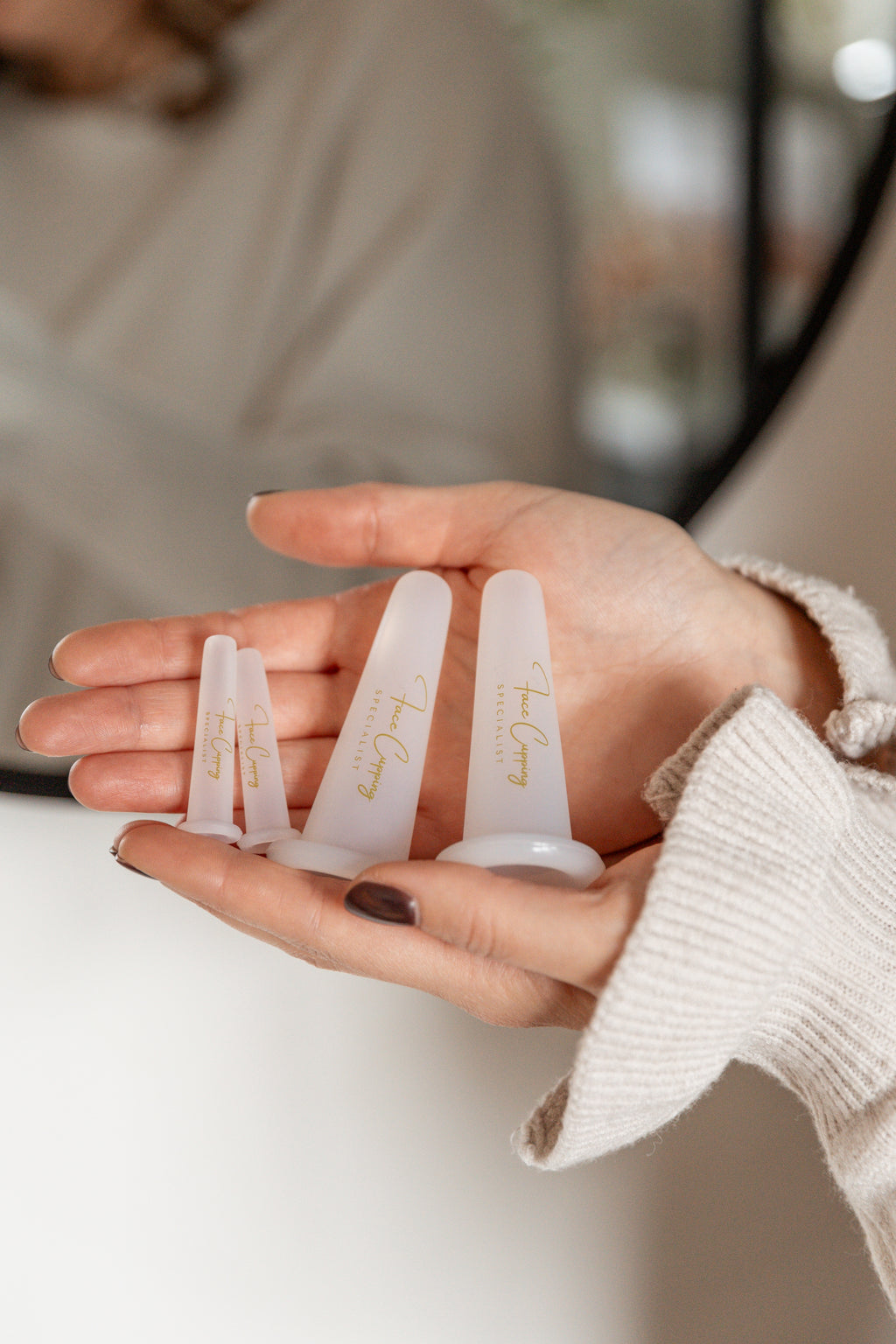 De Face Cupping Specialist houdt de Cups vast in haar handen voor de spiegel.