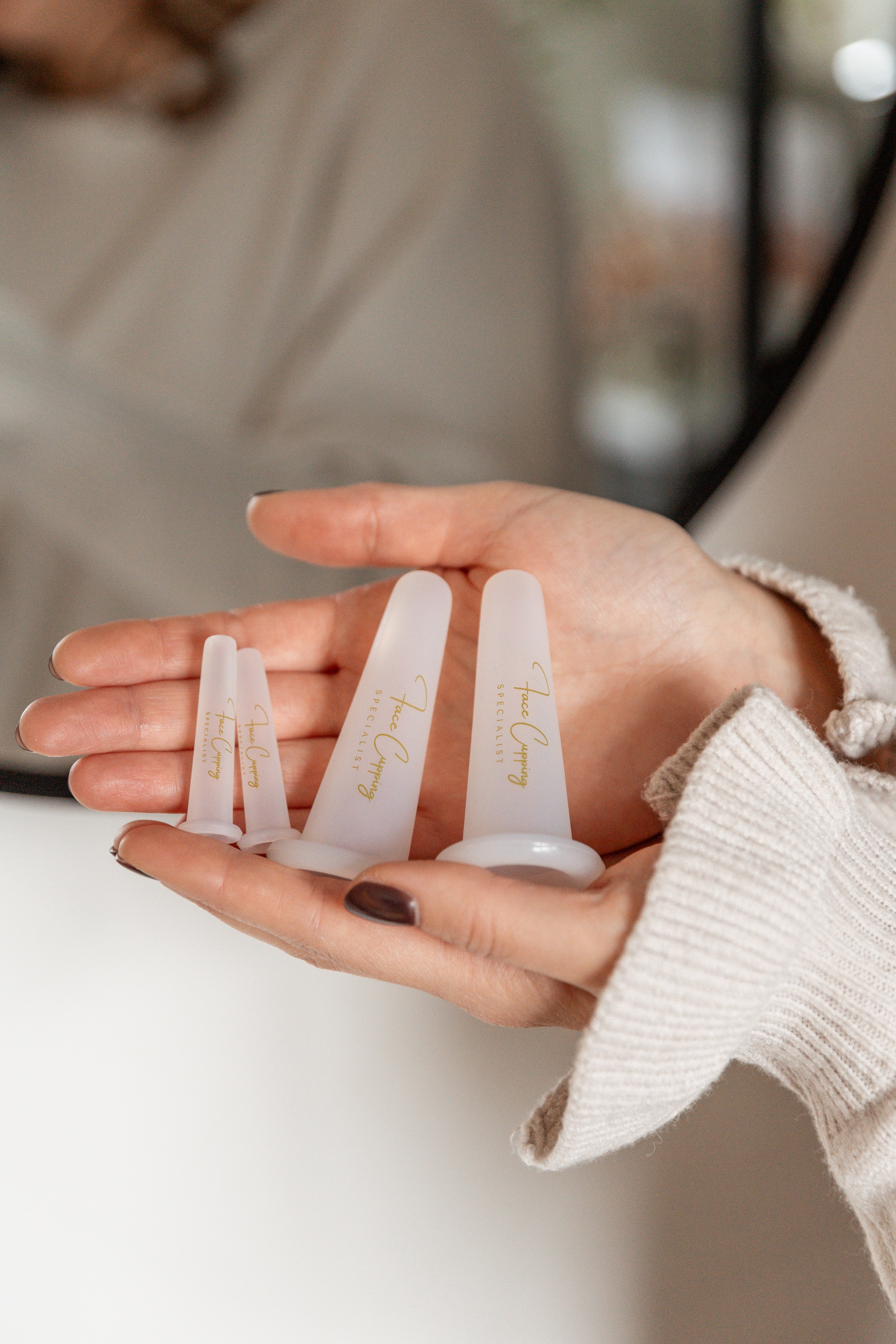 De Face Cupping Specialist houdt de Cups vast in haar handen voor de spiegel.